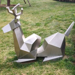 Stainless steel sheep sculpture lying on the green land of the park