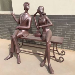 Bronze sculpture of young men and women sitting on bench in street park