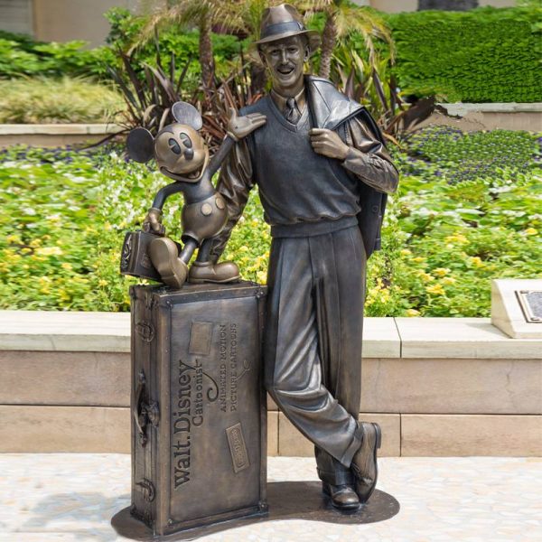 Bronze statue of a middle-aged man wearing a hat on the street in an outdoor park