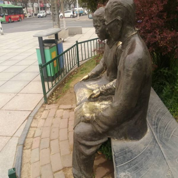 Bronze sculpture in an outdoor park showing two elderly people sitting side by side on a stone bench - Image 4