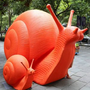 Red fiberglass snail sculpture in outdoor places such as parks and gardens in front of shopping malls